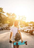 Young girl with a skateboard on a car park. photo