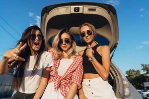 Three young woman posing for the camera the car park. photo