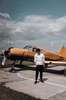 A man standing on the background of a small single engine plane. photo