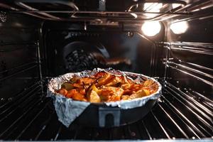 Baked potatoes with carrot and other spices in roasting pan. photo