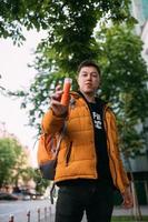 Young adult man in a yellow jacket and jeans walks on a city street photo