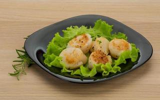 Grilled scallops on the plate and wooden background photo