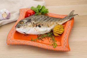 Grilled dorado on the plate and wooden background photo