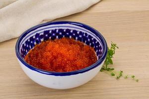 Red caviar in a bowl on wooden background photo