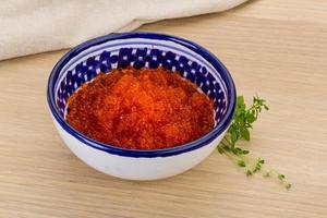 Red caviar in a bowl on wooden background photo