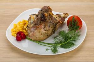 Roasted turkey leg on the plate and wooden background photo