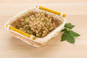 White currant in a basket on wooden background photo