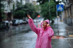 joven mujer sonriente con impermeable mientras disfruta de un día lluvioso. foto