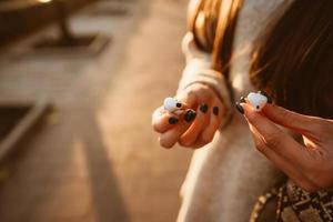 Beautiful young girl holding wireless headphones in park photo