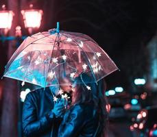 chico y chica besándose bajo un paraguas foto