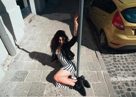 Beautiful fashionable lady sitting on old street photo