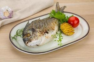 Grilled dorado on the plate and wooden background photo