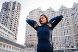 Young sporty woman doing exercises with rubber band outdoor photo