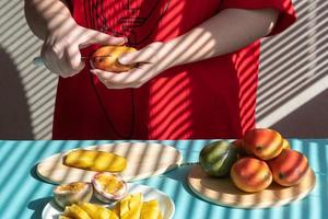 manos femeninas cortan mango y fruta de la pasión, desayuno de frutas foto