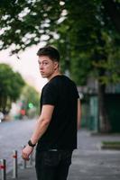 Young adult man in a black t-shirt and jeans walks on a city street photo