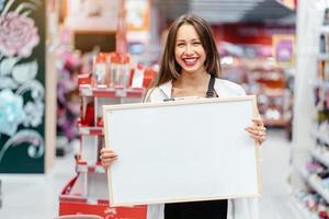 mujer morena sonriente sosteniendo tablero en blanco blanco foto