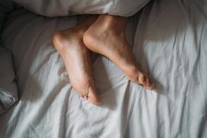Close-up woman feet alone in white bed photo