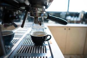 Little cup of espresso standing in the steel coffee machine photo