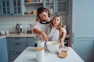 mom teaches her little daughter to cook food photo