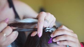 Process of braiding. Master weaves braids on head in a beauty salon, close up photo