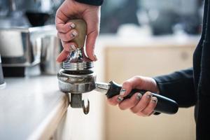 Barista presses ground coffee using tamper. photo