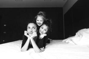 Mom and two daughters have fun on the bed photo