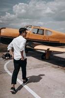 A man standing on the background of a small single engine plane. photo