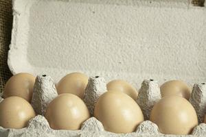 caja de papel con huevos de gallina frescos de granja sobre fondo de tela de saco foto