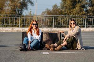 mujeres jóvenes con bolsas de compras sentadas en el estacionamiento foto