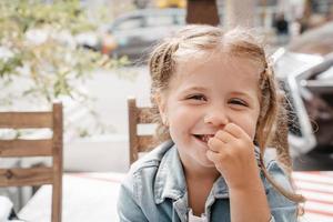 Little girl in a street cafe with french fries photo