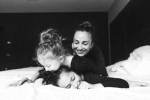 mamá y sus dos hijas se divierten en la cama foto