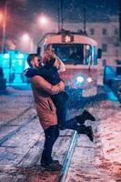 pareja de adultos jóvenes en la línea de tranvía cubierta de nieve foto