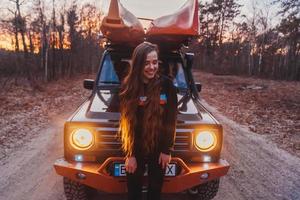 mujer se encuentra frente a un vehículo todoterreno 4x4. foto