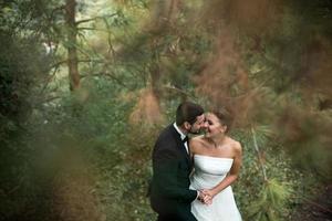 la novia y el novio bailan juntos en el bosque foto