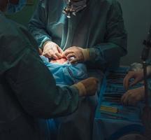 Surgeon and his assistant performing cosmetic surgery on nose photo