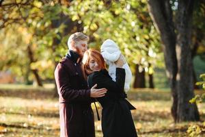 familia joven e hijo recién nacido en el parque de otoño foto