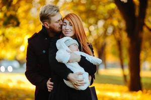 familia joven e hijo recién nacido en el parque de otoño foto