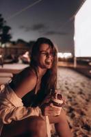 Young woman is sitting on chair at night beach photo