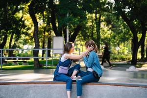 dos niñas felices sentadas en el parque de patinaje foto