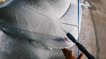 Young man covered soap suds on his car photo