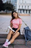 Cheerful young woman taking notes while sitting on steps otdoors photo