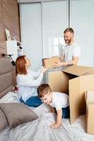 Dad mom and little son play in the bedroom with paper boxes photo