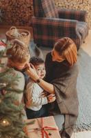 Young caucasian family mom dad son near fireplace christmas tree photo