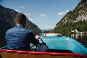 Handsome young guy controls a motorboat on a mountain lake photo