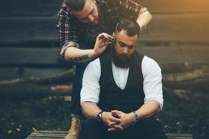 barber shaves a bearded man in vintage atmosphere photo