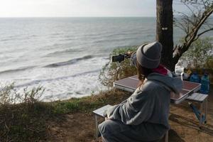 mujer joven toma una foto en un teléfono inteligente del paisaje marino