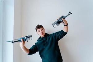 Guy holds two quadrocopters against a wall photo