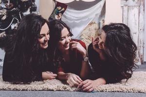 hermosa chica comiendo galletas de navidad y bebiendo té mientras está acostado en una alfombra. apartamento vintage decorativo. foto