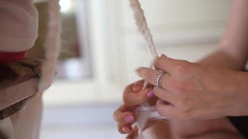 A female hairdresser weaves a braid from a white kenekalon. Close up of the process