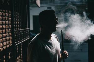 Silhouette of hookah maker blowing smoke in the dark. photo